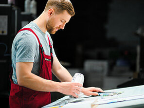 Man worker measuring printing color with spectrometer on the operating desk of the printing plant